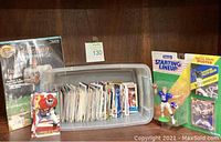 Full view of football collectible lot including plastic bin of football cards, two original-packaging Starting Lineup figures, and 1995 Collecting Figures magazine.
