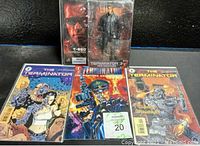 Photo showing Terminator T-850 action figure in original packaging with Arnold Schwarzenegger likeness along with three Terminator related comic books.