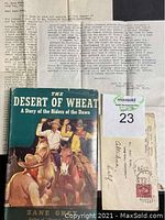 Typed letter pages spread out behind the book with envelope visible, showing document condition and details including postage stamp.