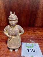 Front view of a vintage heavy metal piggy bank figurine showing its full body, apron, and headwrap details.