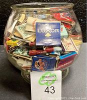 Glass bowl filled with numerous vintage matchbooks showing a Luxor Las Vegas matchbook on the outside.
