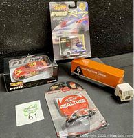 Four die-cast cars including large Allied Van Lines truck and three NASCAR racing cars in original packaging.