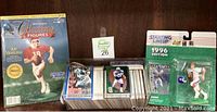 Photo of Joe Montana Collecting Figures booklet, box of assorted football trading cards, and 1996 Starting Lineup football action figure in packaging.