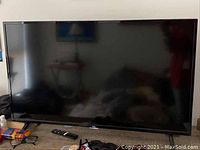 Front view of the TCL 40-inch flatscreen TV showing screen and remote on table.