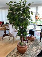 Full view of the faux plant in basket planter placed indoors, showing the overall height and fullness of foliage.