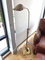 Full-length view of lamp showing square base, column, adjustable joint and shell-shaped shade