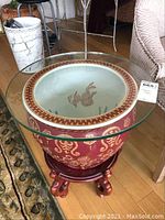 Full front view of the side table showing the glass top and planter with wooden stand.