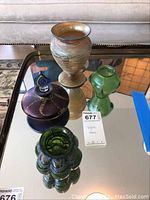 Overhead photo showing all four glass items arranged on a mirrored surface, highlighting their varying shapes and colors.