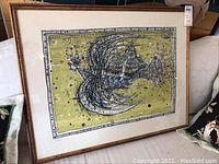 Overall view of framed print leaning on sofa, showing full artwork and frame condition