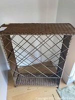 Side view of metal and wicker wine rack showing the woven top surface and metal lattice sides.