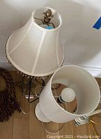 Two table lamps seen from above showing a beaded fabric shade on one and a plain white fabric shade on the other, along with a single tassel.