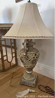 Front view of the lamp showing complete beige shade and ornate base detail