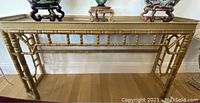 Front view of gold tone console table with spindle leg design.