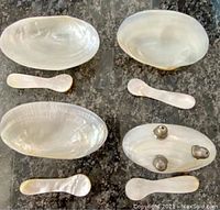 Four mother of pearl oval caviar cups each paired with a matching mother of pearl spoon, cups have sterling silver footed bottoms visible