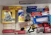 Drawer contents showing various food wraps, candles, tools, Lysol wipes, and first aid kit