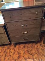 Full front view of dresser showcasing four drawers and tapered legs, brown Formica finish.