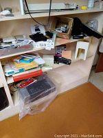 Office shelf with assorted items including an OWC Mercury Pro external CD/DVD drive box, boxes of paper, memory sticks, SupraFax 288 modem, LG monitor, and a black 3-hole punch.