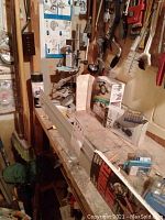 Photo of drill press mounted on workbench with various tools and supplies around it.