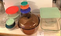 Full view of all items in the lot showing the Dutch oven, bread pan, casserole dish, and nested glass storage containers with colored lids.
