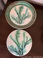 Three pieces of Edgecomb Pottery showing seaweed design on plates and trivet.