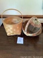 Two handmade baskets, one square with handle and one round, displayed side by side on a table.