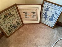 Photo showing all three framed cross stitch pieces together on the floor; one with numbers and figures, one with a quote, one with alphabet and dancing couple.