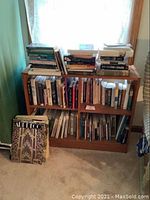 Wide view of wooden bookcase filled with various books and 'Art Deco' book leaning in front of the left side