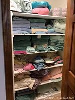Photo showing stacks of bath towels and folded sheets and blankets on shelves of the linen closet.