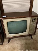 Front angled view of vintage Sylvania wood grain TV console showing curved CRT screen and control knobs.