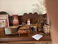 Wide view of vintage wooden music boxes and pottery vases arranged on a wooden surface with a decorative backboard