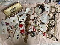 Photo showing wide range of vintage costume jewelry with earrings, bracelets, chains, pins, and boxed item