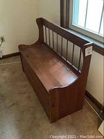 Side view of the vintage all wood bench showing curved armrest detail and vertical spindle backrest.