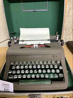 Gray Royal portable manual typewriter with paper loaded in roller, showing keyboard and front view.