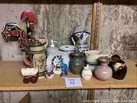 Photo showing wooden rooster figure, ceramic beer stein, chipped sangria pitcher, blue and white pitcher, various small vases and jars on shelf against unfinished wall.