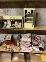 Wooden doll cradle containing dolls and folded doll clothes and linens on shelf