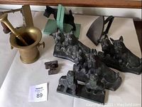 Brass mortar and pestle, antique metal irons, various vintage metal Scotty dog door stops and bookends including elephant and Scotty dog designs on white background.