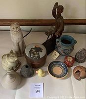 Overview of all pottery and craft pieces in the lot including sculptures, pottery vessels, and decorative boxes.