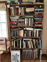 Wide shot showing a loaded bookshelf packed with assorted books spanning multiple shelves and genres including art, fashion, and history.