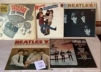 Photo showing five vintage vinyl record albums featuring Beatles, Monkees, and Herman's Hermits. Album covers vary in design and condition.