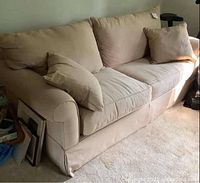Front view of beige fabric sofa bed with matching cushions and pillows, displaying overall good condition.