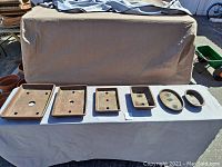 Seven ceramic bonsai planters displayed in a row on a white sheet, showing range of shapes and sizes.