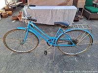 Side view of vintage blue Schwinn Suburban cruiser bicycle showing frame, tires, seat and handlebars.