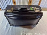 Closed top view of black leather flight briefcase showing Delta Air Lines branding and combination locks.
