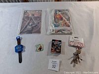 Photo showing RoboCop 2 comic, Superman comic, digital watch, card deck, and two figurines.