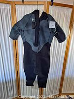 Front view of the XCEL Hawaii wet suit in dark grey and black, short sleeves and short legs, hanging for display.