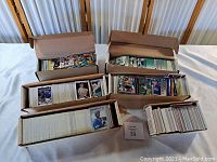 Five cardboard storage boxes and one small box arranged on table showing loose cards