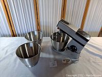 Kenwood Chef mixer with three stainless steel mixing bowls set out on table