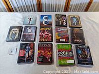 Full lot of 13 music and movie DVDs arranged on white tablecloth, showing all DVD covers clearly.