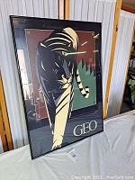 Front view of framed modern art print showing abstract tiger design in black, beige, brown, green colors and 'GEO' text at bottom.