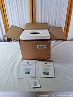 Box opened showing the ceramic steamer with styrofoam protection and two instruction manuals placed in front.